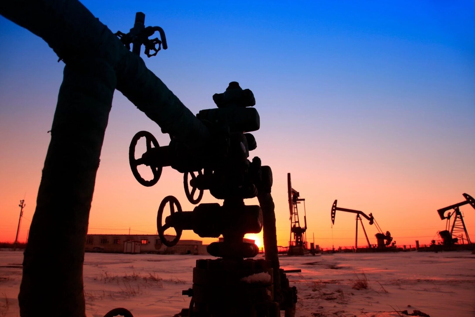 A view of an oil field with the sun setting.